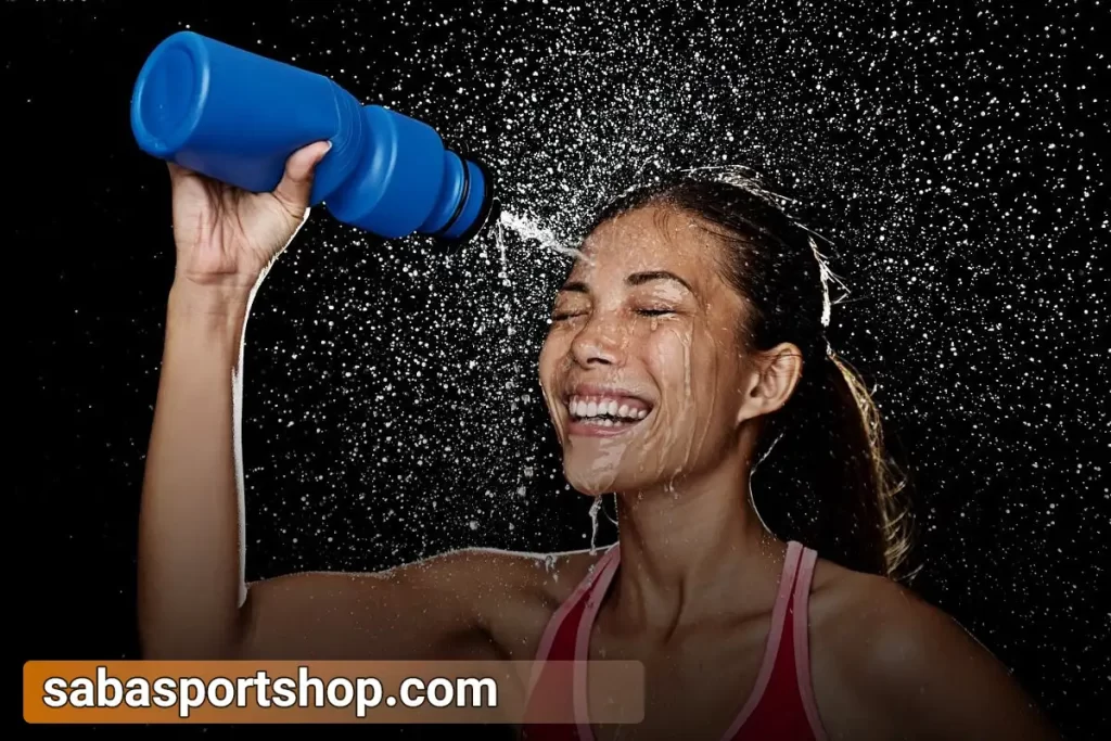 یک دختر در حال پاشیدن آب به صورت خود با قمقمه ورزشی آبی رنگ